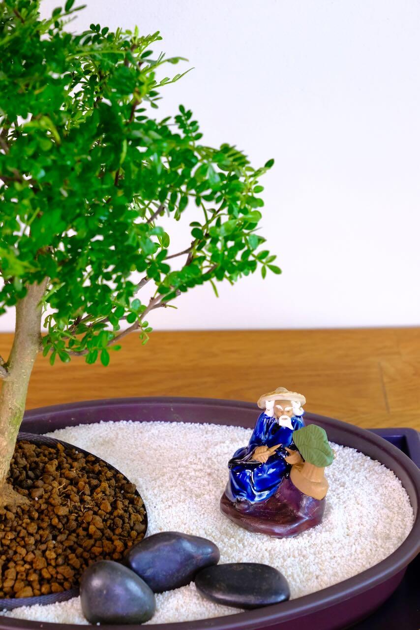 Close up of the figurines pruning bonsai included with this zen bonsai garden